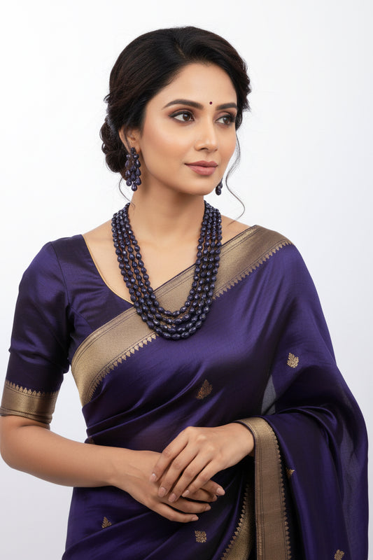 A woman wearing a purple saree, showcasing The Blue Sapphire Briolette Pearl Shaped Necklace, styled elegantly.