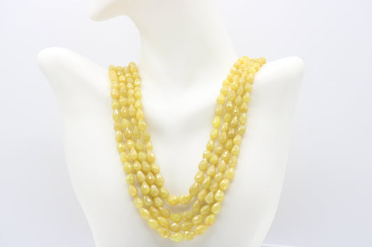 The Yellow Sapphire Briolette Pearl Shaped Necklace displayed on a bust, showcasing its elegant yellow stones.