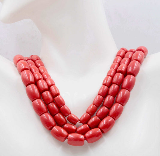 Natural coral beads strand necklace displayed elegantly on a mannequin, showcasing reddish-orange semi-translucent beads.