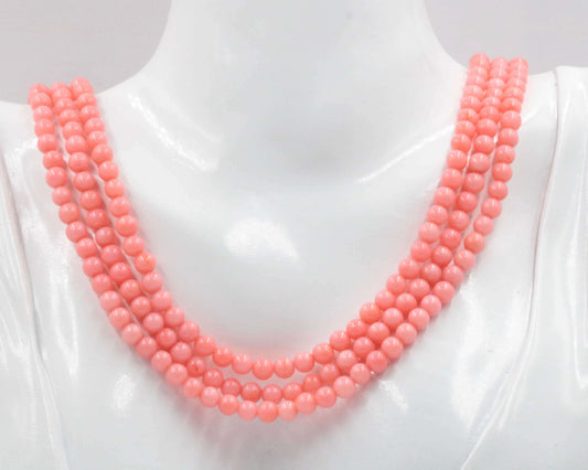 Natural pink coral beaded necklace displayed on a mannequin with multiple strands and a soft pink hue.