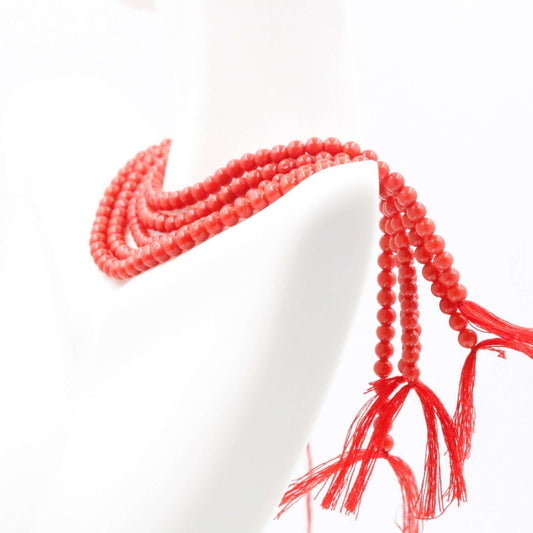 Natural red coral beads strand elegantly displayed on a mannequin, showcasing their vibrant color and texture.