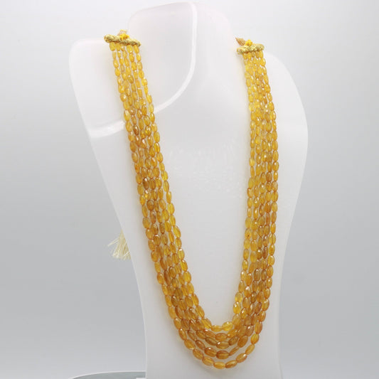 Natural yellow sapphire necklace with multiple strands displayed on a stand.