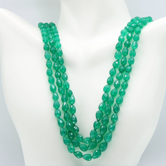 Emerald pear shape faceted necklace displayed on a mannequin with three strands of green gemstones.