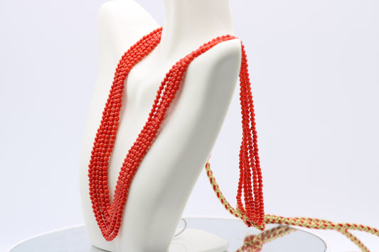 Coral necklace 3mm round -5 strands displayed on a mannequin showcasing its reddish orange color and polished finish.