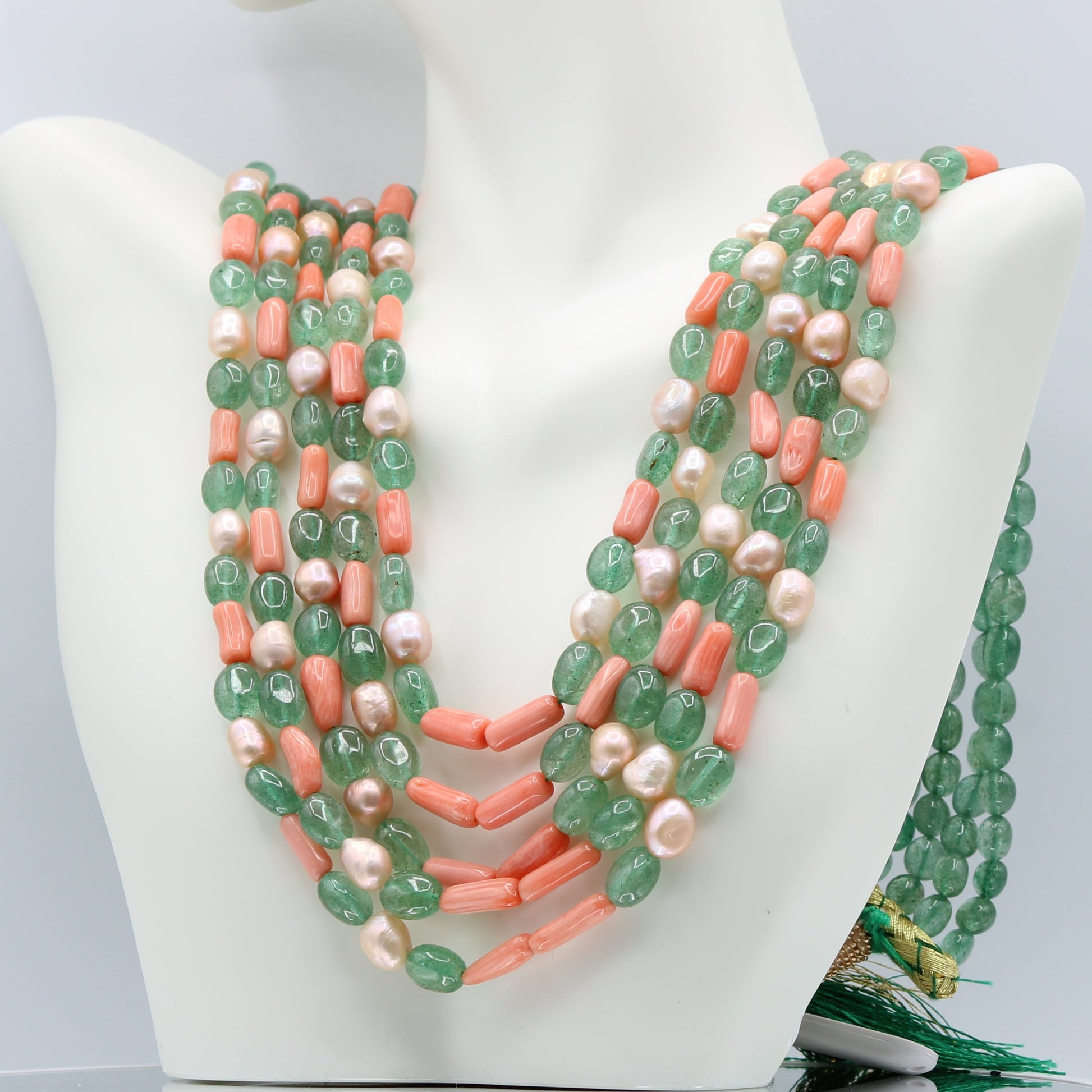 Russian Emerald with FWP and coral layered necklace displayed on a bust.