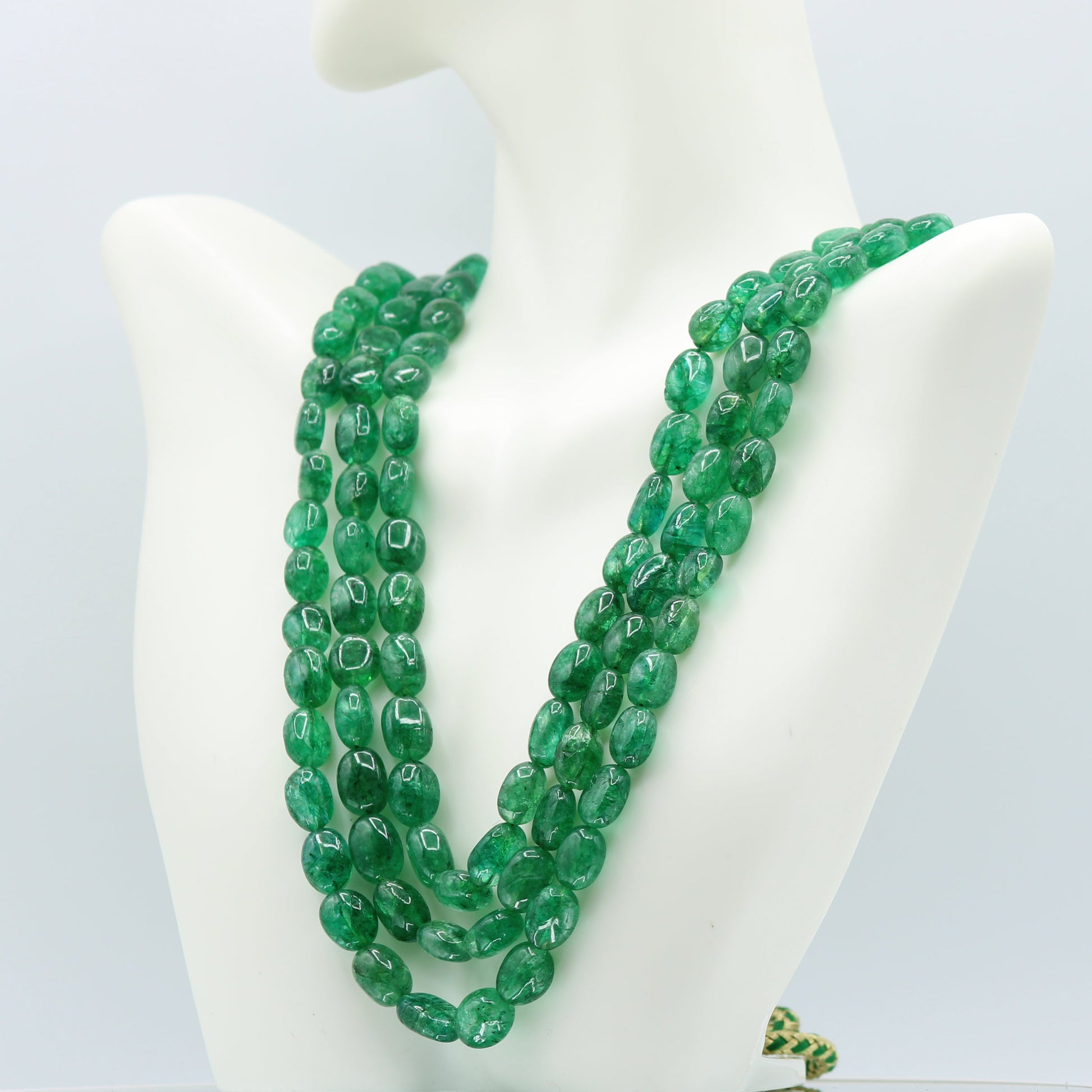 Emerald oval beaded necklace showcasing deep green polished beads on a display bust.