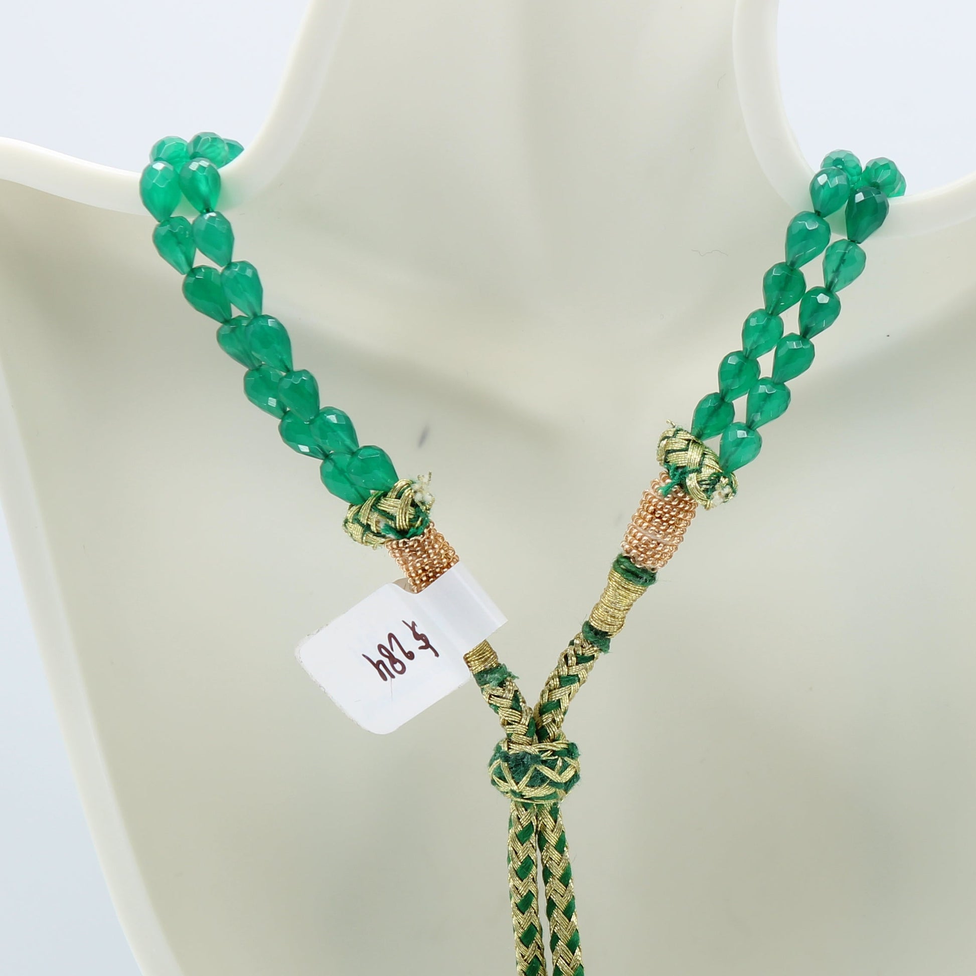Emerald pear shape faceted necklace featuring semi-transparent green beads on a woven string.