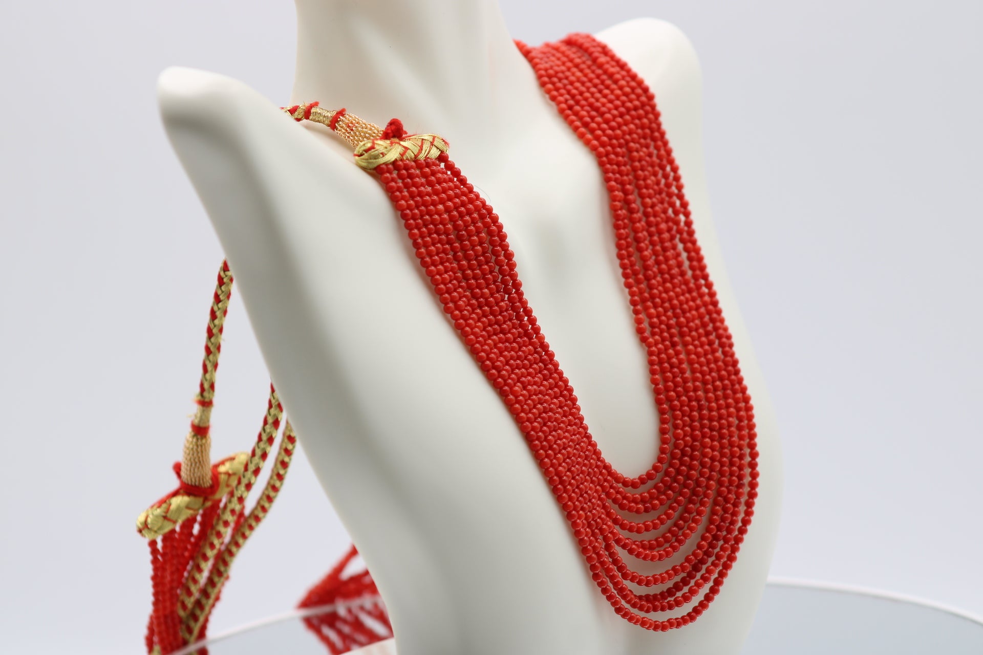 Elegant coral necklace 2mm displayed on a jewelry stand with multiple strands of polished coral beads.
