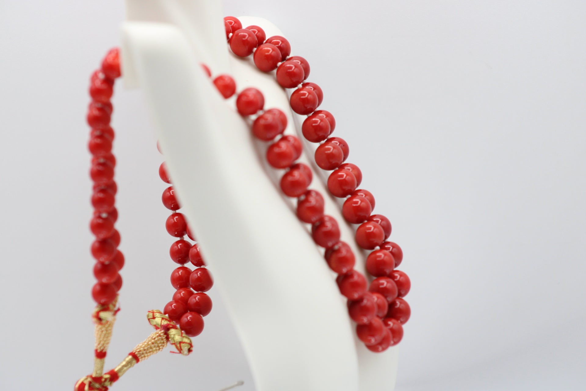 Natural orange coral gemstone necklace displayed on a mannequin with vibrant red beads.