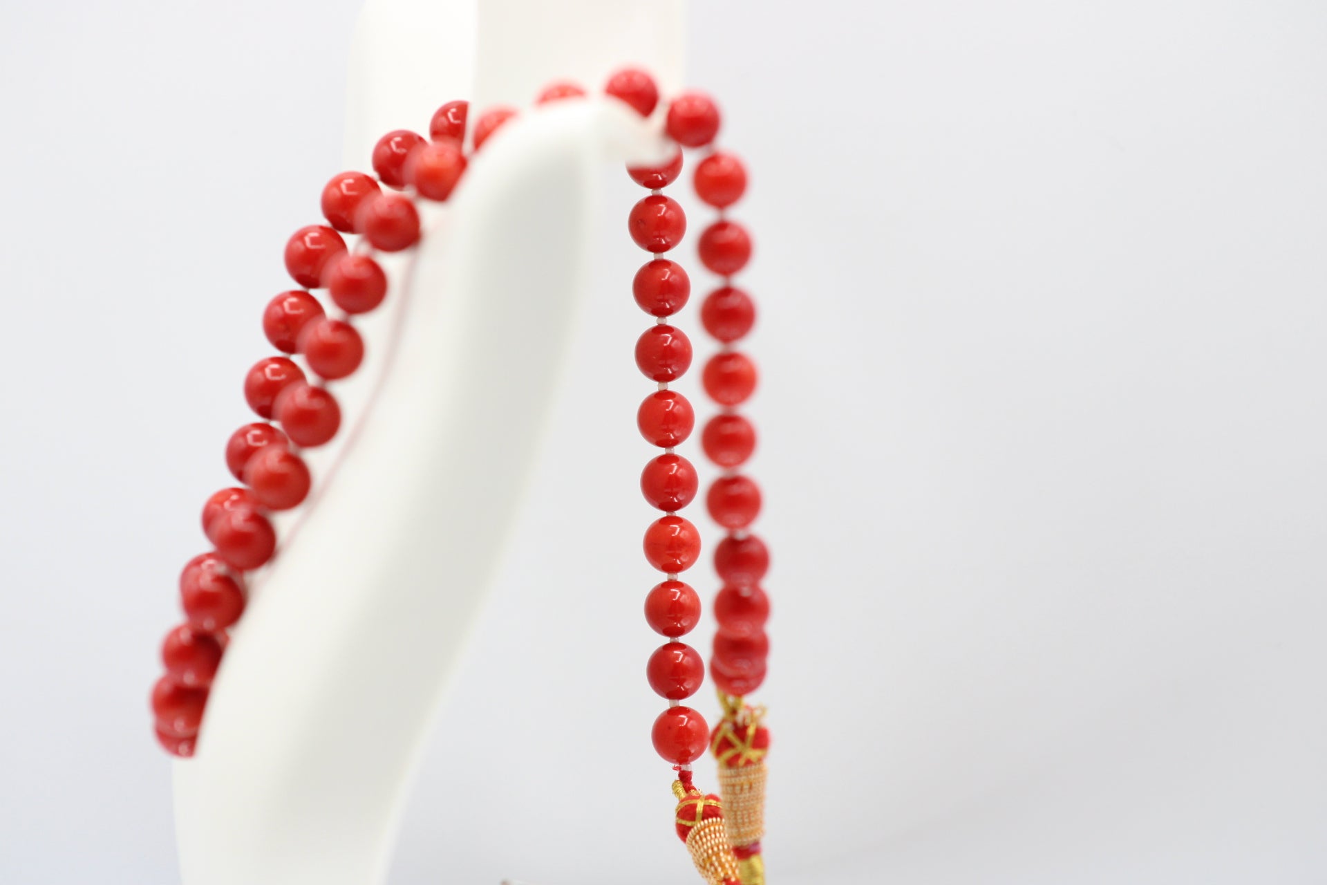 Natural orange coral gemstone necklace displayed on a mannequin with multiple strands.