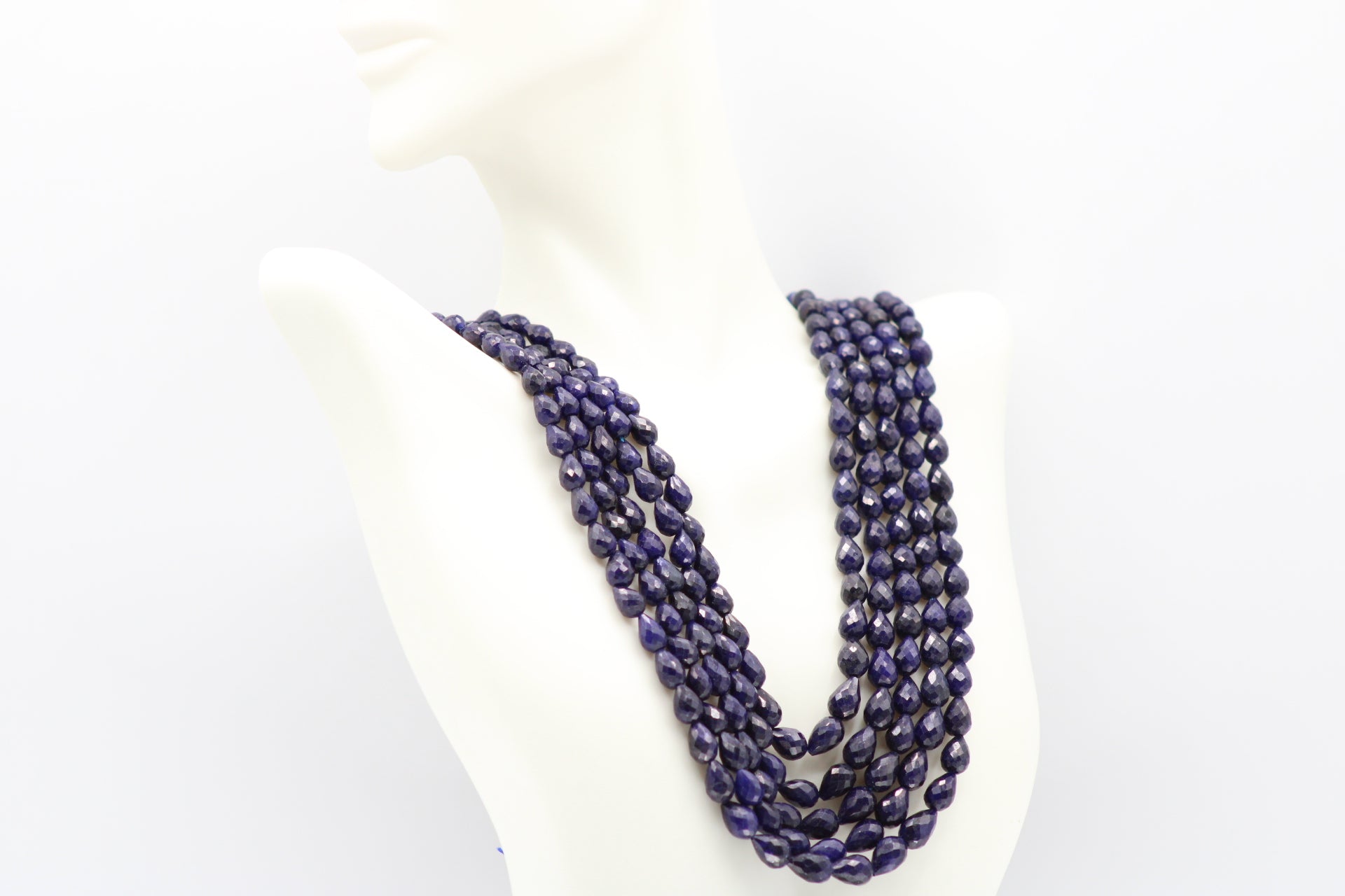 The Blue Sapphire Briolette Pearl Shaped Necklace displayed on a mannequin, showcasing its elegant design and deep blue color.