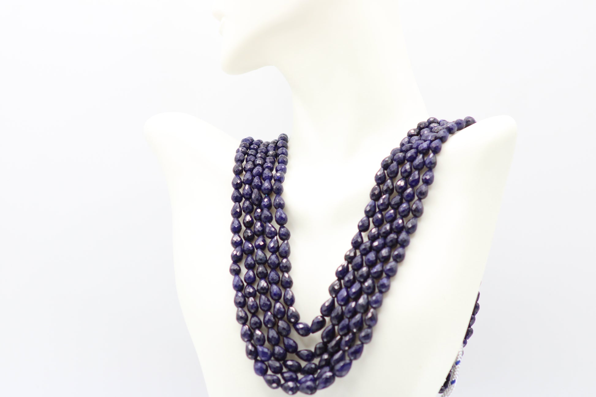 The Blue Sapphire Briolette Pearl Shaped Necklace displayed on a mannequin with elegant layers of deep blue sapphires.