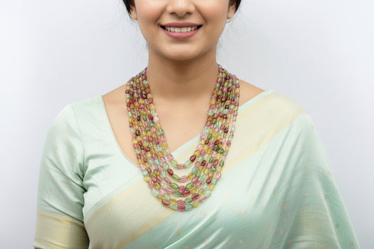 Tourmaline multi-color beaded necklace worn by a smiling woman in a light green saree.