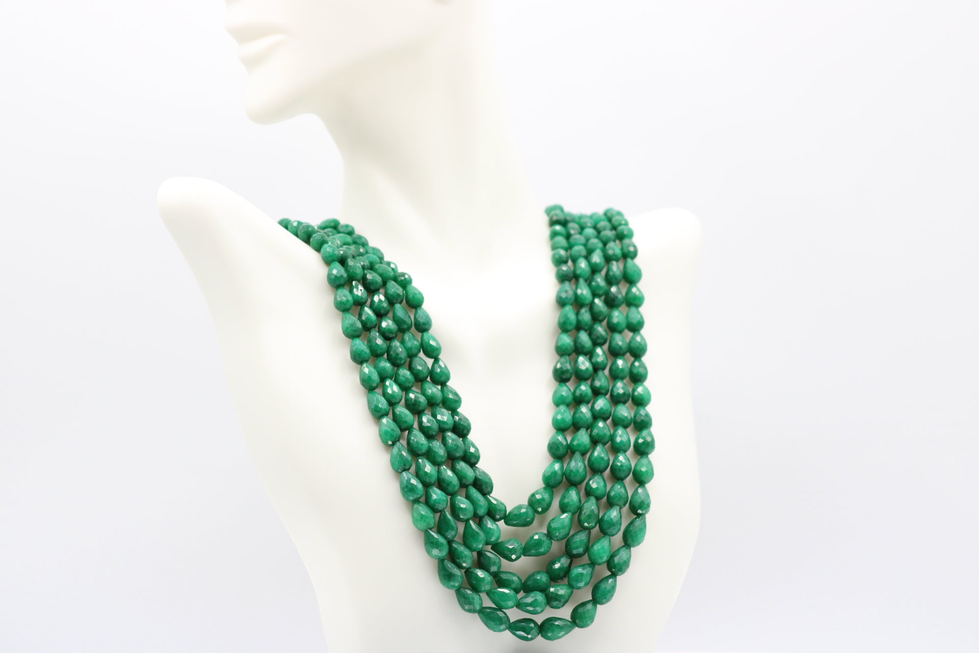 The Dark Green Sapphire Briolette Pearl Shaped Necklace displayed on a mannequin with multiple strands of green gemstones.