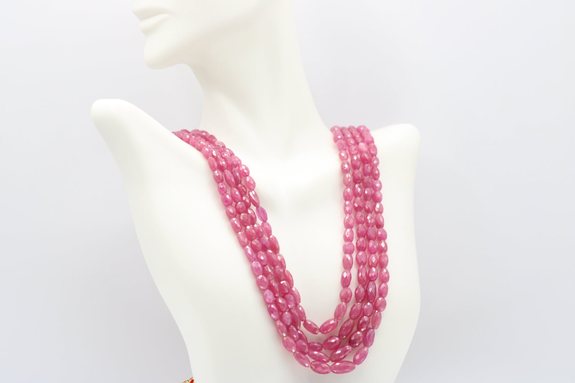 The Pink Sapphire Faceted Necklace displayed on a mannequin, showcasing its elegance and vibrant pink color.