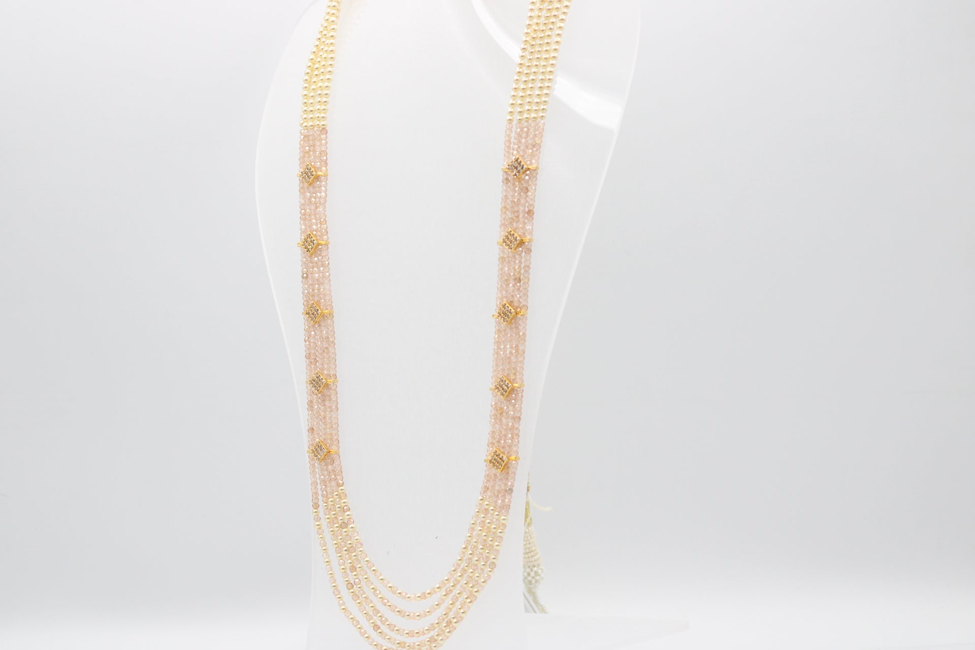 Cubic Zirconia & Pearl Necklace displayed on a clear stand, showcasing its elegant multi-strand design.