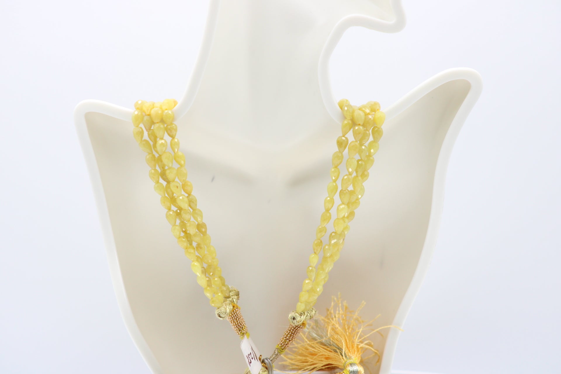 The Yellow Sapphire Briolette Pearl Shaped Necklace displayed elegantly on a mannequin with yellow gems.