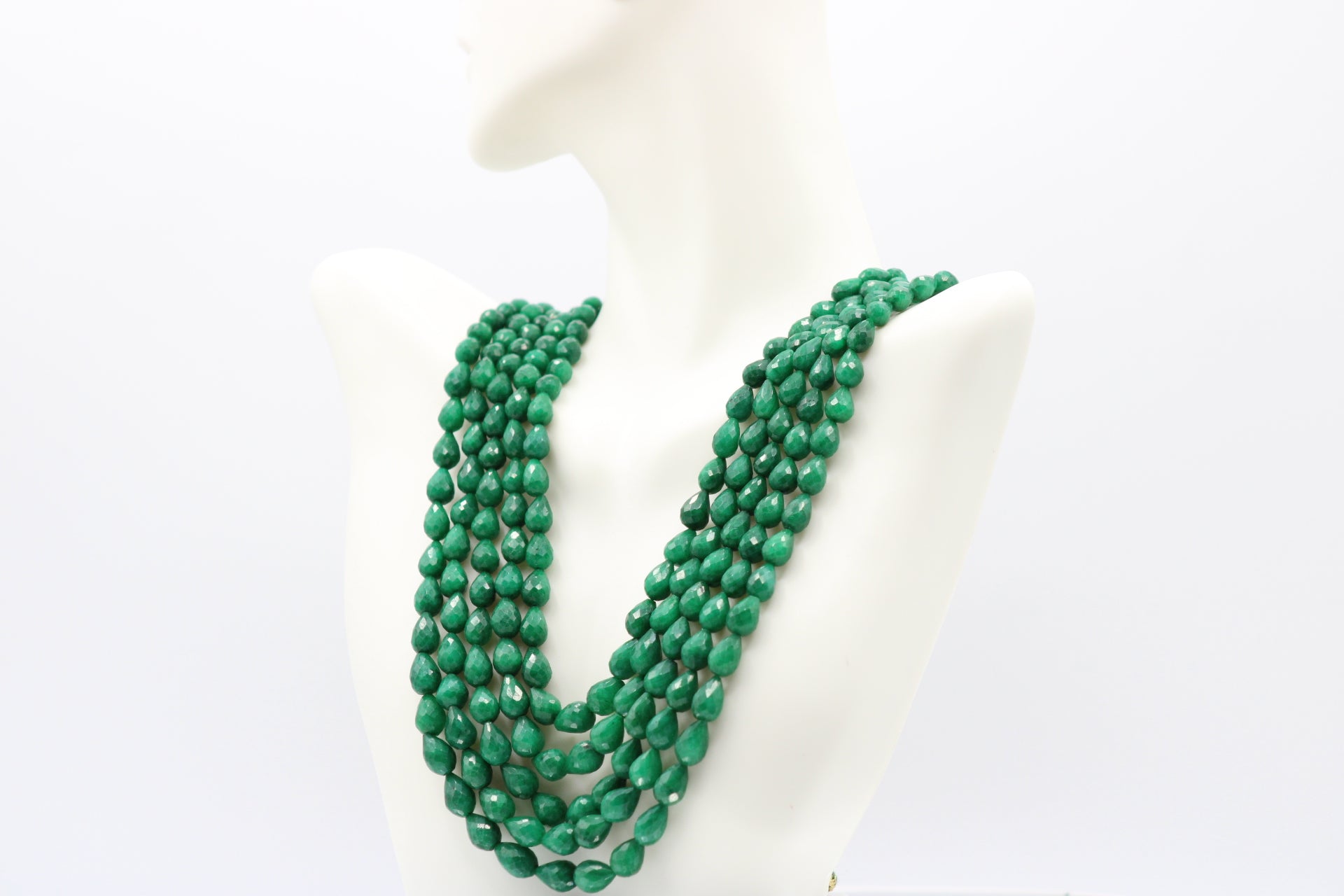 The Dark Green Sapphire Briolette Pearl Shaped Necklace displayed on a mannequin with multiple strands of dark green gemstones.