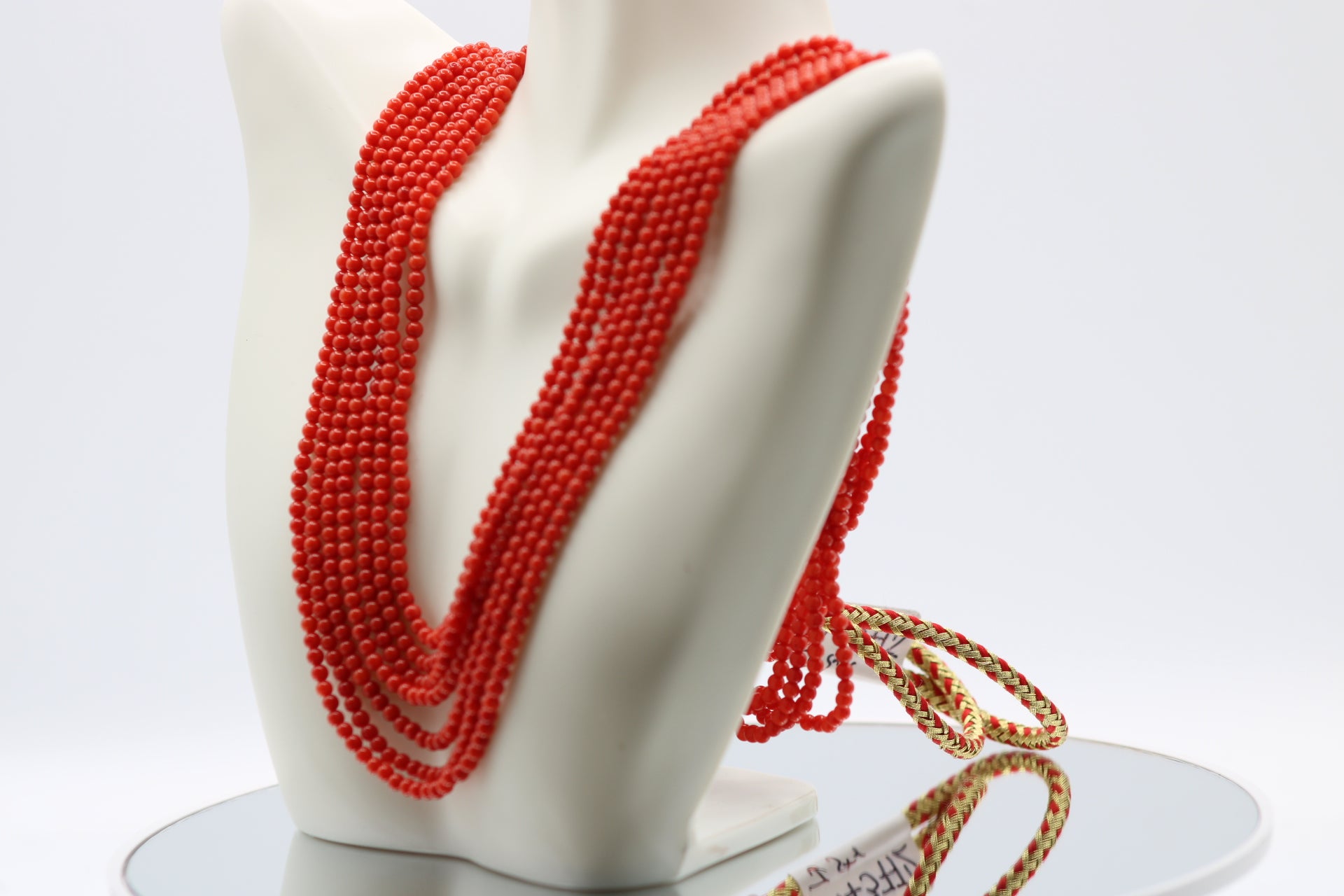 coral necklace 3mm round strands displayed on a bust, featuring seven strands of polished coral beads.
