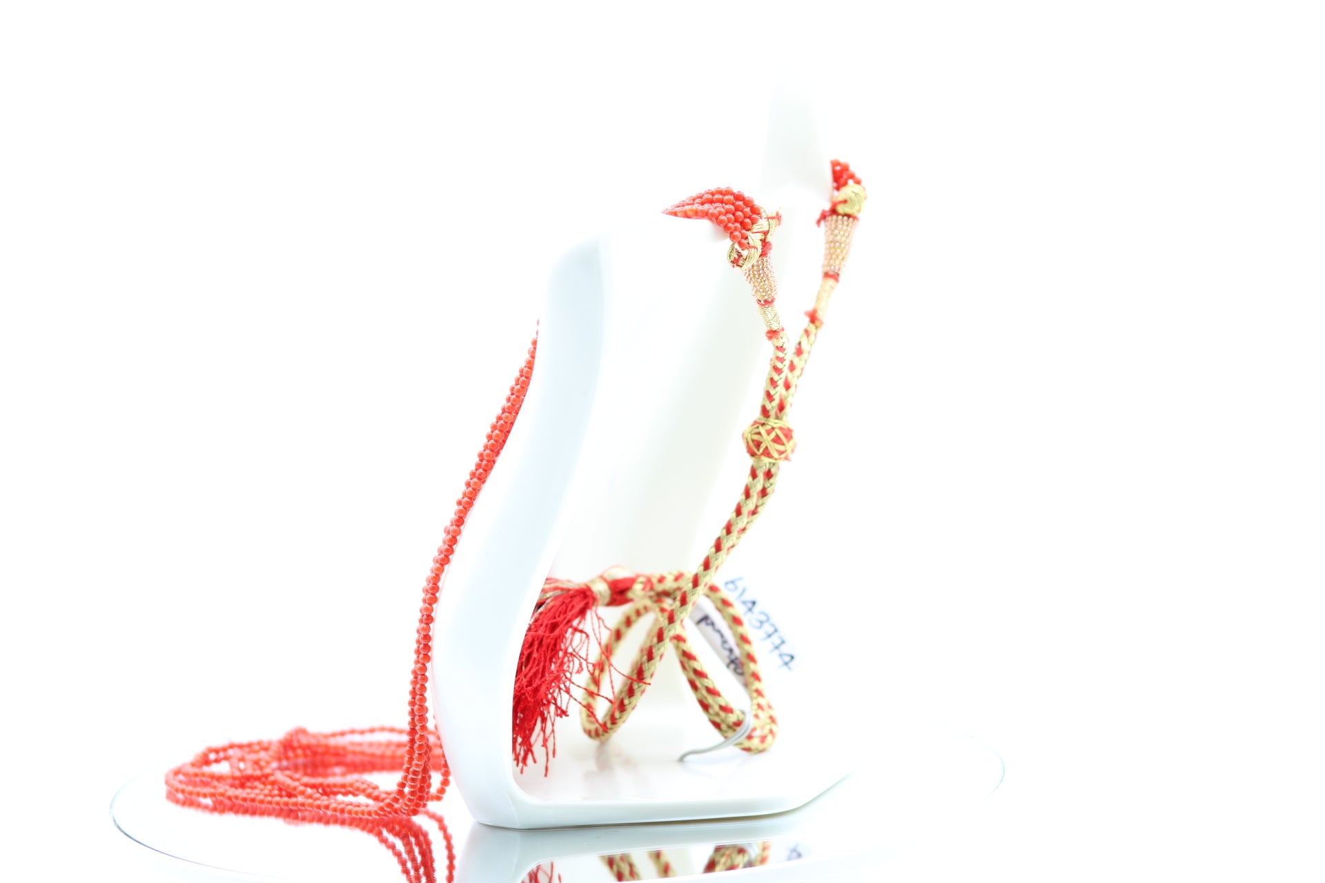 5 strand coral necklace displayed elegantly on a white stand, showcasing reddish orange gemstones.