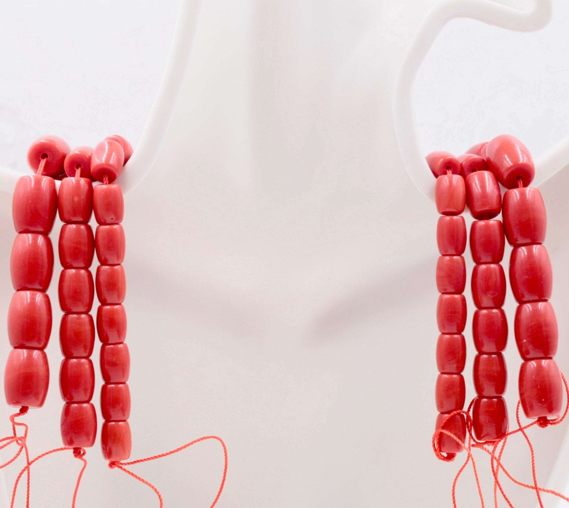 Natural coral beads strand displayed on a mannequin, showcasing their reddish orange color and semi-translucent appearance.