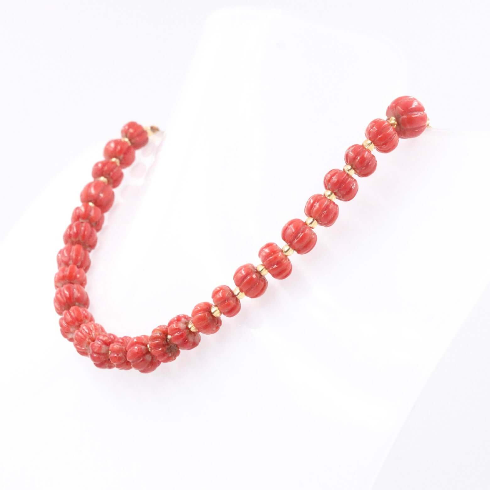 Natural Italian coral beads necklace showcasing red coral pumpkin strands on a display bust.