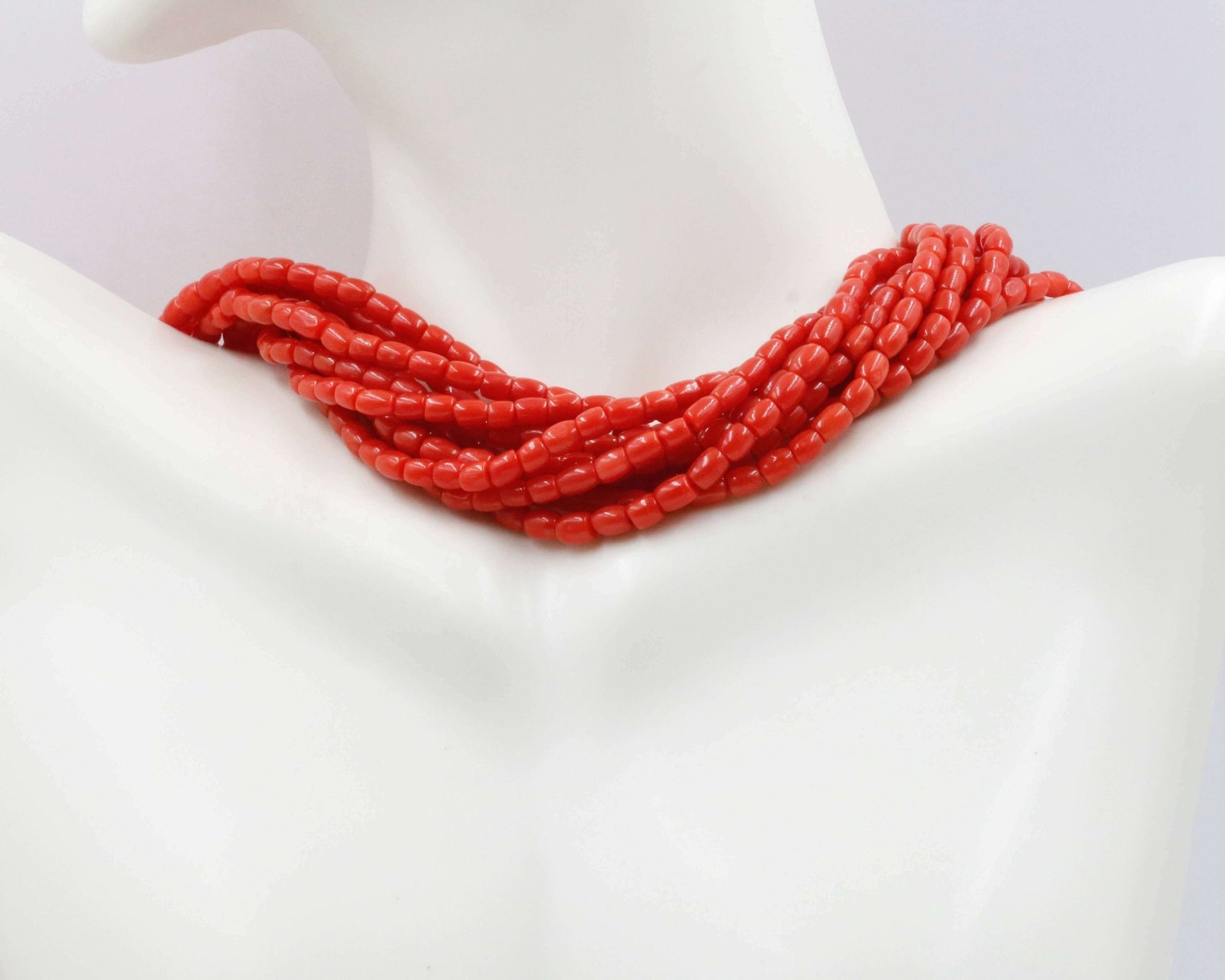 Italian Red Coral Beads Strands worn as a necklace on a mannequin, showcasing their vibrant red color.