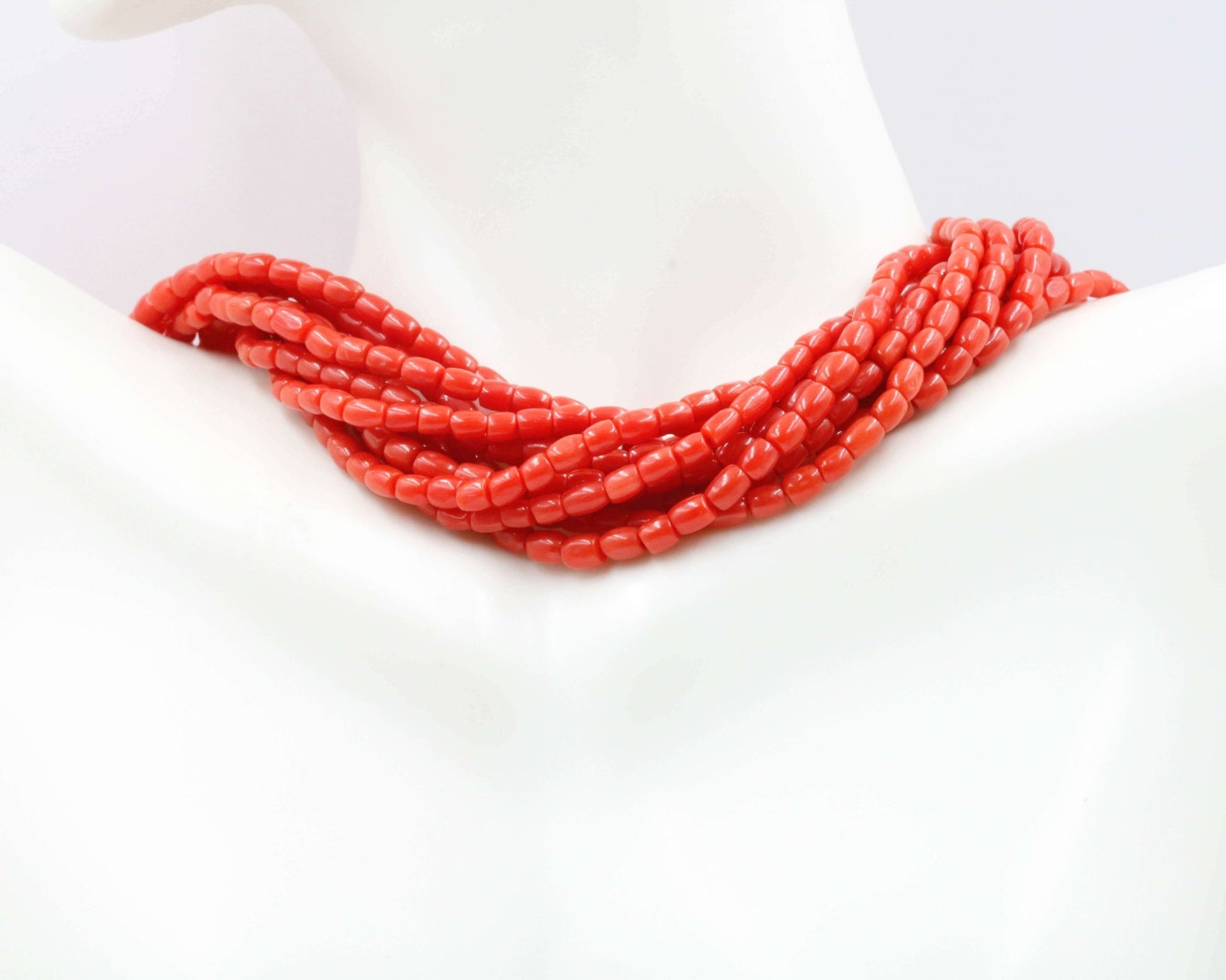 Italian Red Coral Beads Strands displayed on a mannequin's neck, showcasing the vibrant red hues of the beads.