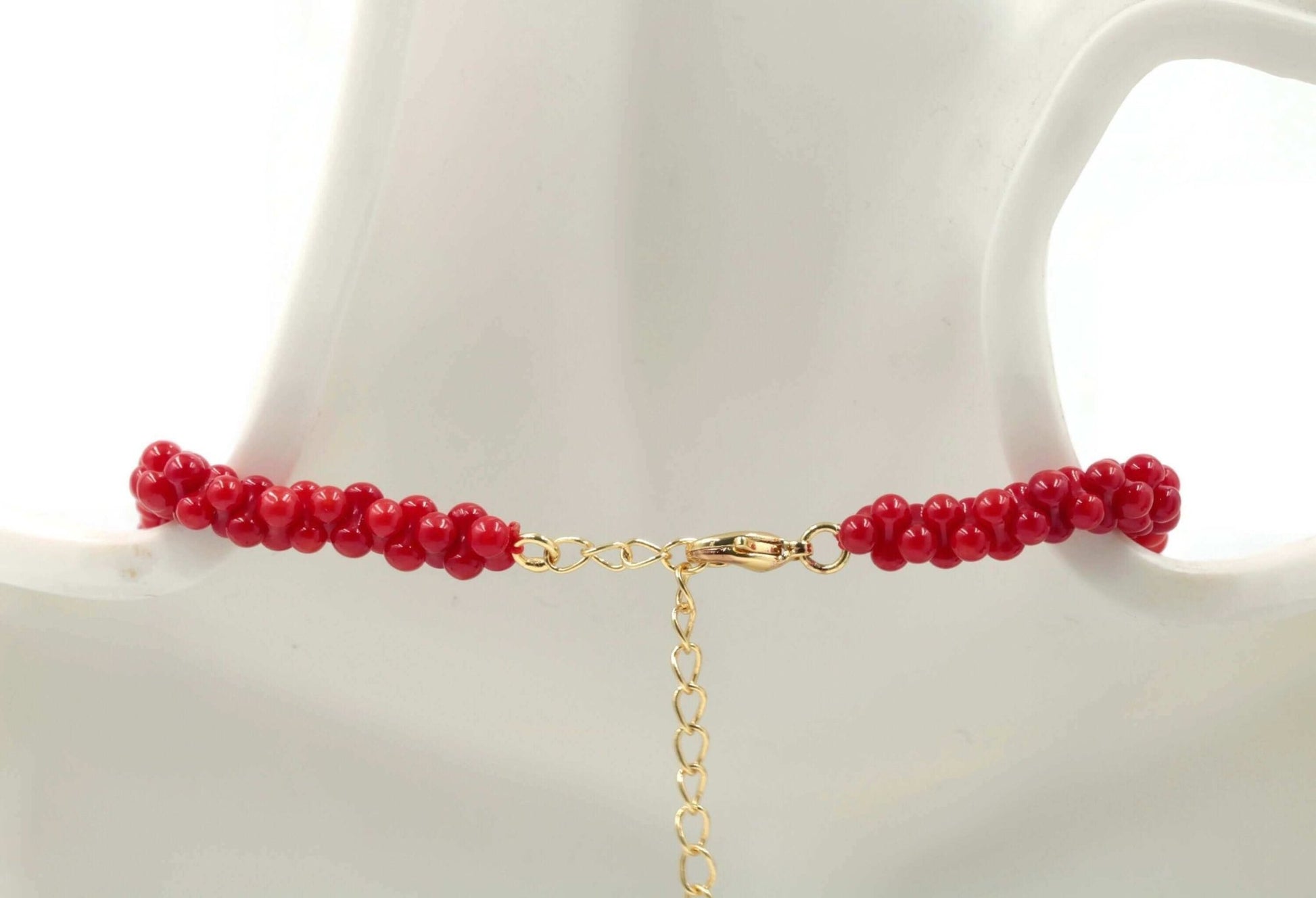 Natural Coral Bead Necklace showcasing vibrant red coral beads with gold clasp detail on a mannequin.