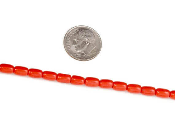 Natural coral beads strand displayed next to a quarter for size comparison.