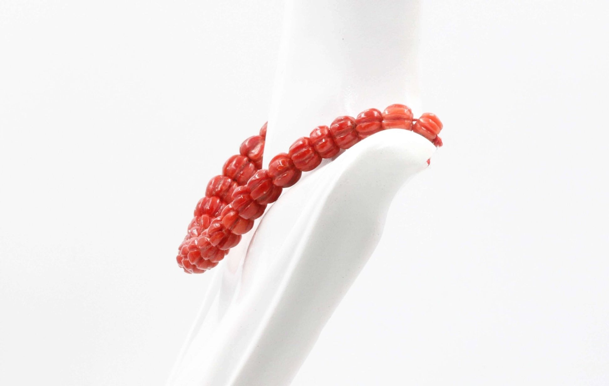 Natural Italian coral beads necklace displayed on a hand model, showcasing vibrant red coral strands.