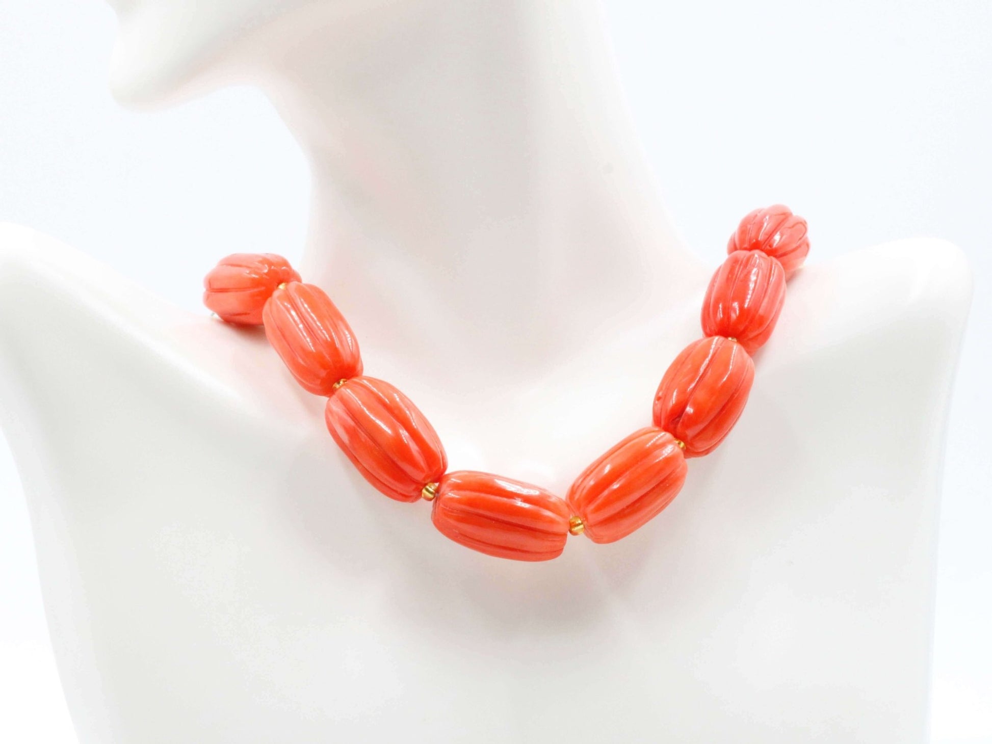 Natural orange coral beads strand displayed on a mannequin neck, showcasing vibrant pumpkin-shaped beads.