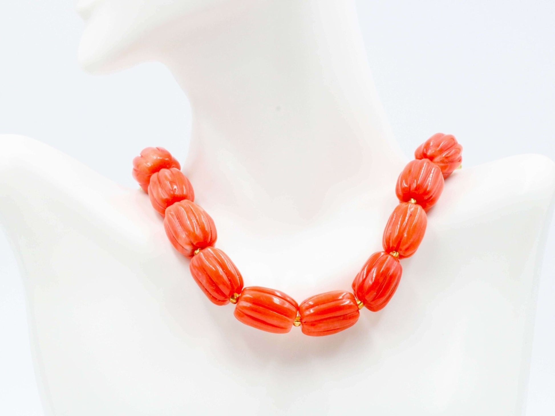 Natural orange coral beads strand displayed on a mannequin, showcasing vibrant pumpkin-shaped beads.