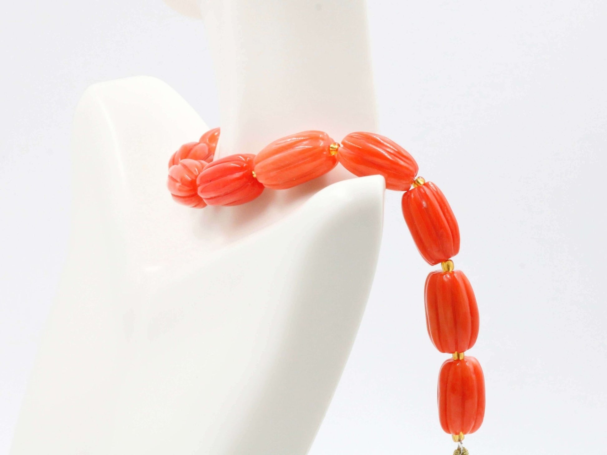 Natural orange coral beads strand displayed on a mannequin showcasing their vibrant color and design.