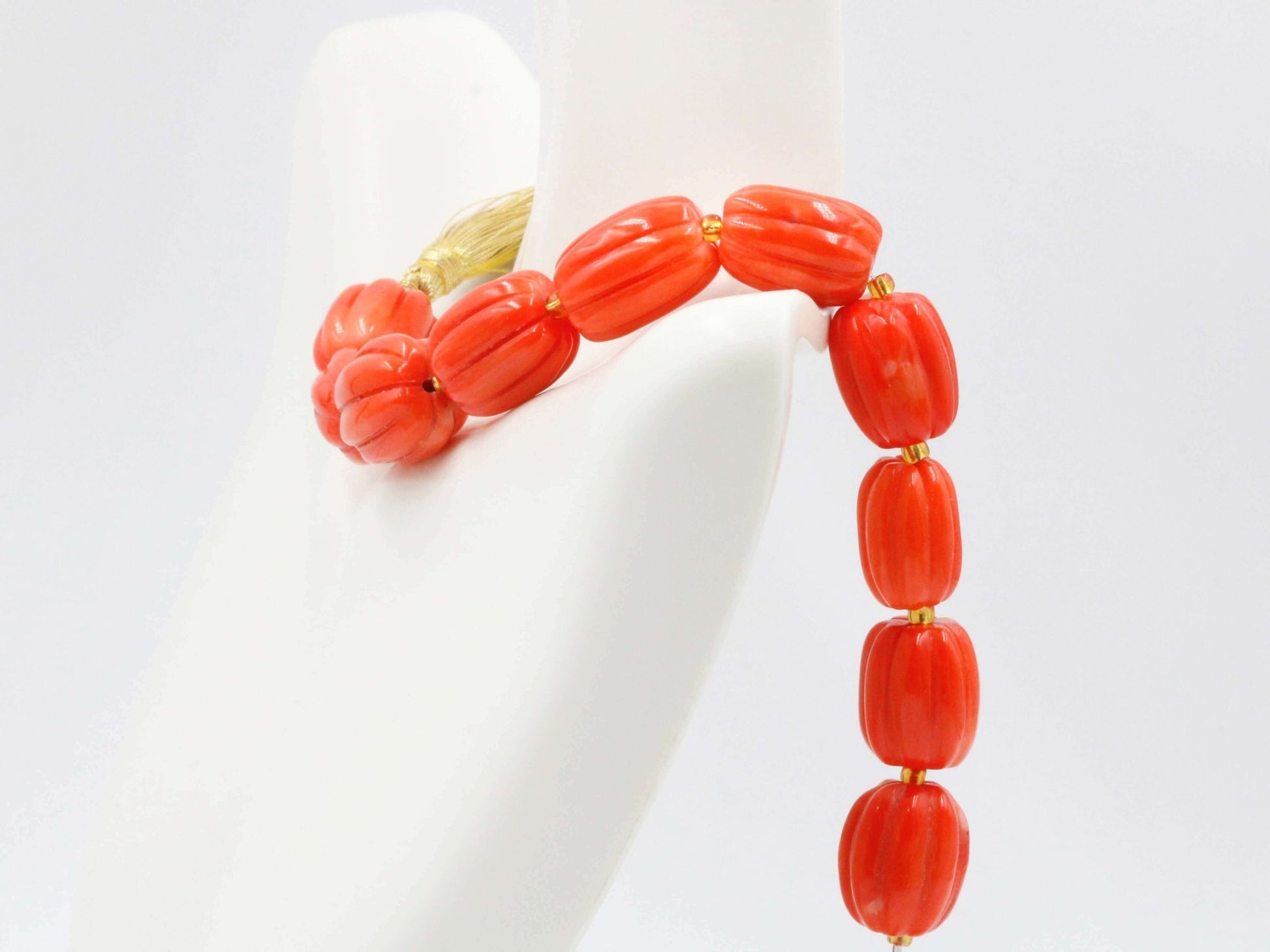 Natural orange coral beads strand showcasing vibrant pumpkin-shaped beads on display.