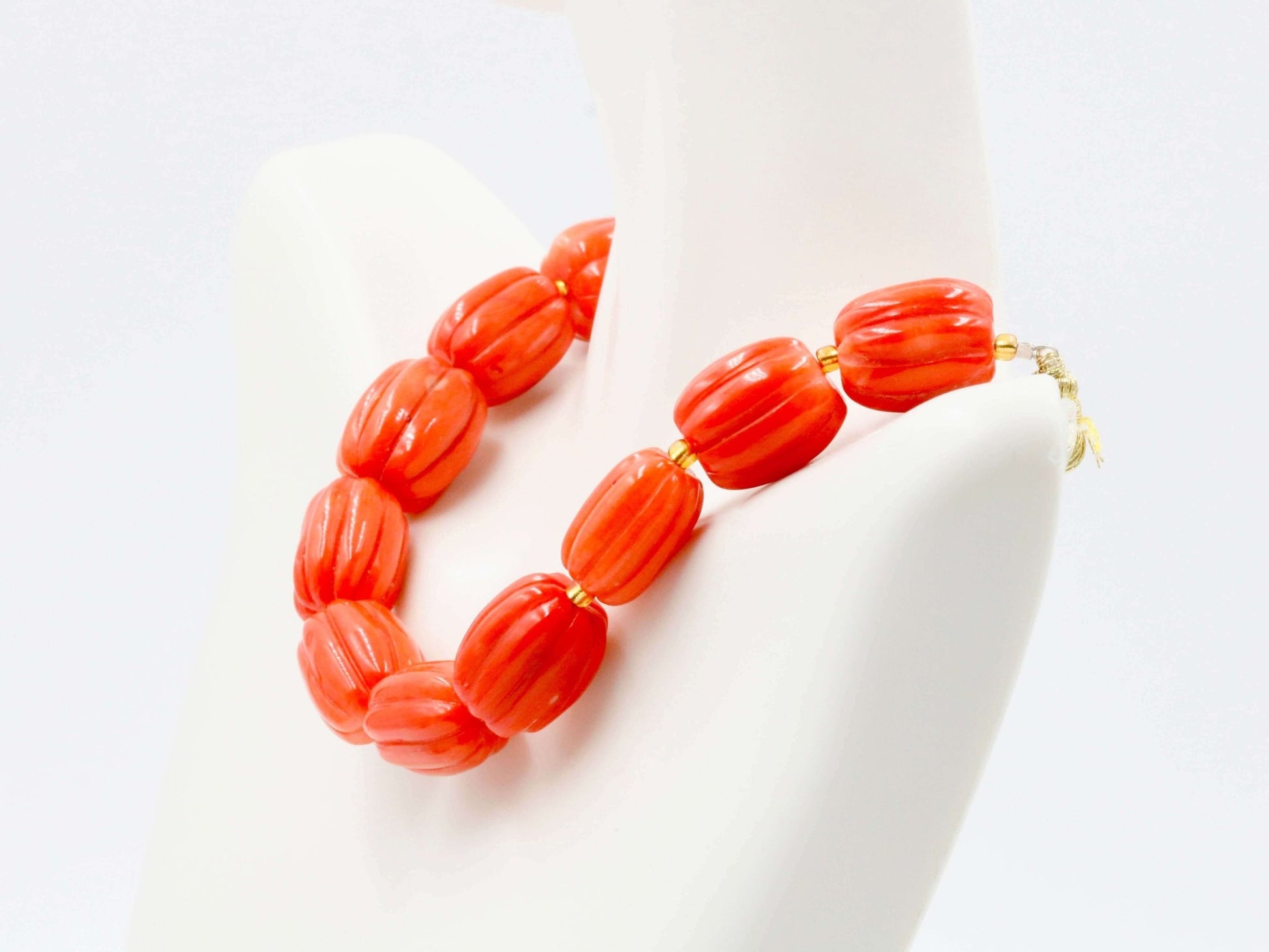 Natural orange coral beads strand displayed on a mannequin for showcasing creativity and warmth.
