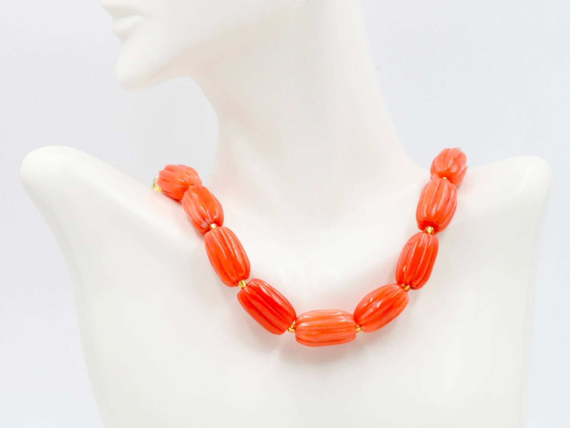 Natural orange coral beads strand displayed as a necklace on a mannequin.