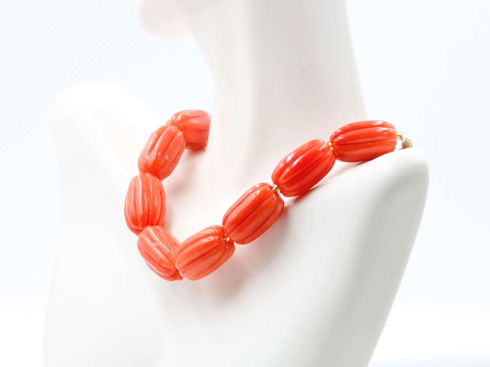 Natural orange coral beads strand displayed as a necklace on a mannequin, showcasing vibrant orange color and unique pumpkin shape.