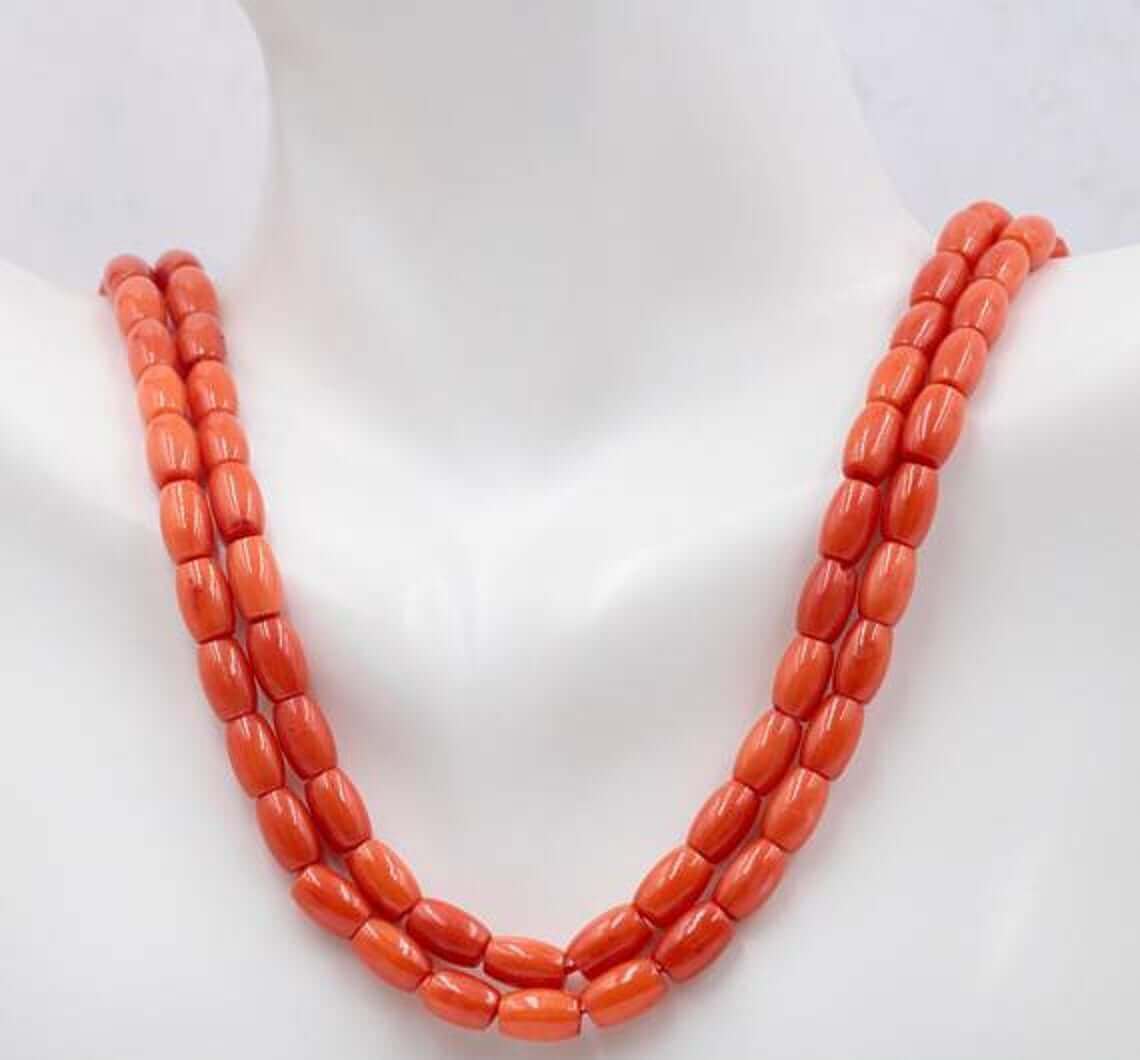 Natural orange coral beads strand displayed on a mannequin, showing vibrant semi-translucent barrel-cut beads.