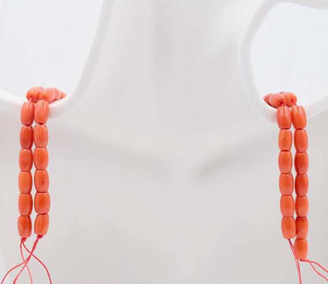 Natural orange coral beads strand displayed on a mannequin, showcasing vibrant semi-translucent beads.