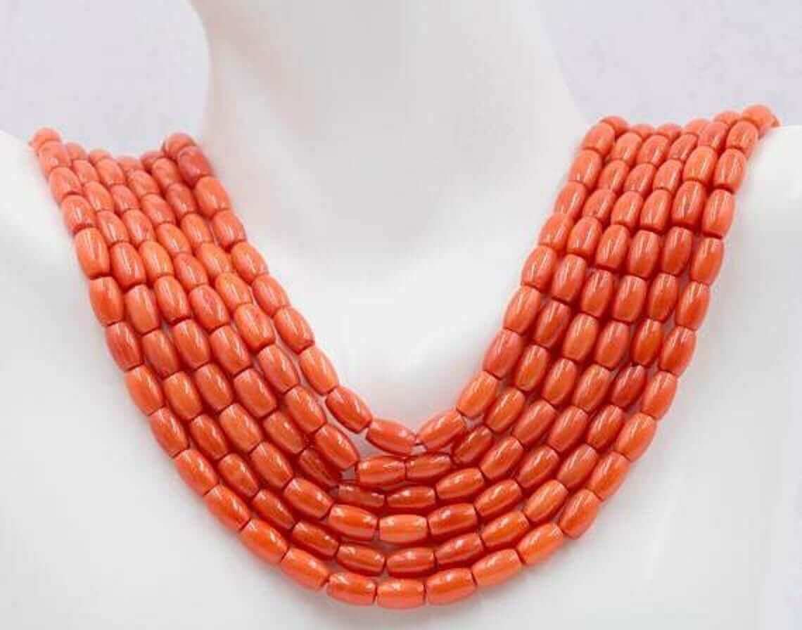 Natural orange coral beads strand displayed on a mannequin, showcasing vibrant orange, semi-translucent barrel cut beads.