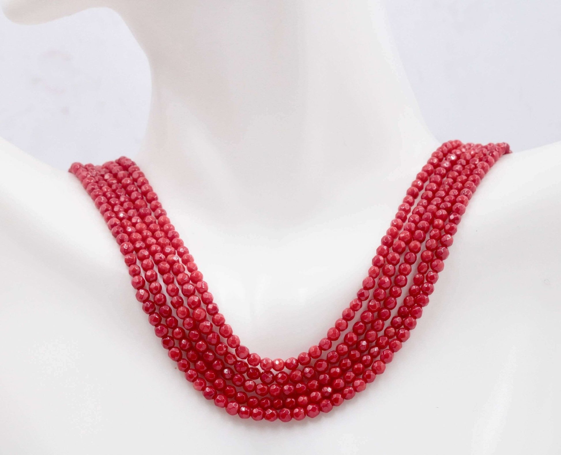 Natural red coral beads strand necklace displayed on a mannequin, showcasing its vibrant red color and beautiful multi-strand design.