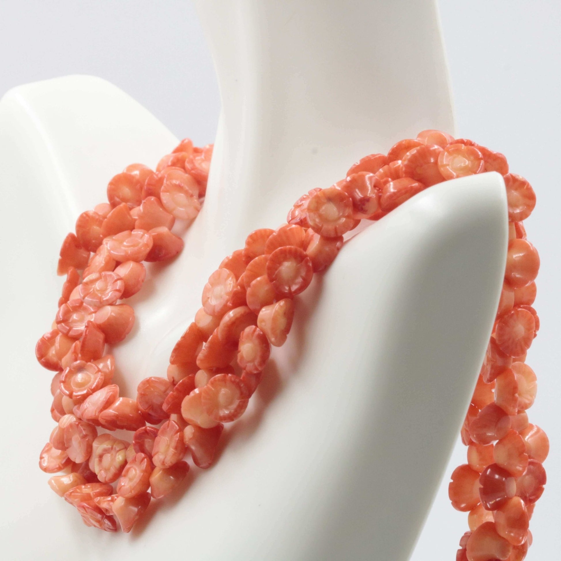 Orange Coral Flower Beads strand displayed on a mannequin, showcasing vibrant hues and intricate flower designs.