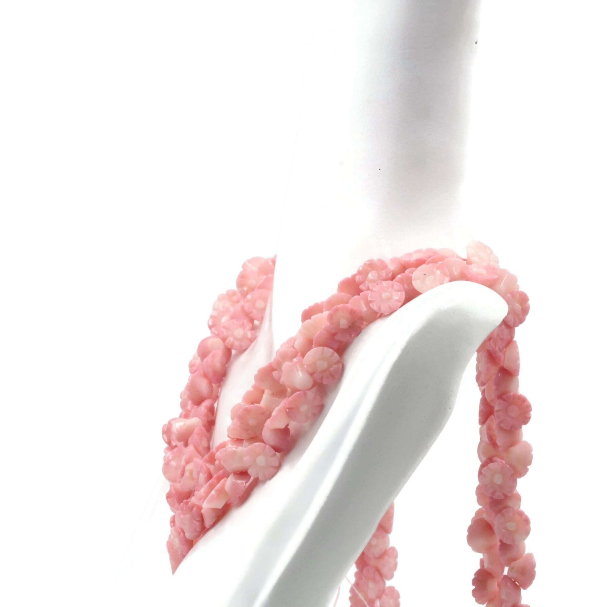 natural pink coral beads strand displayed elegantly on a mannequin, showcasing floral carved designs.